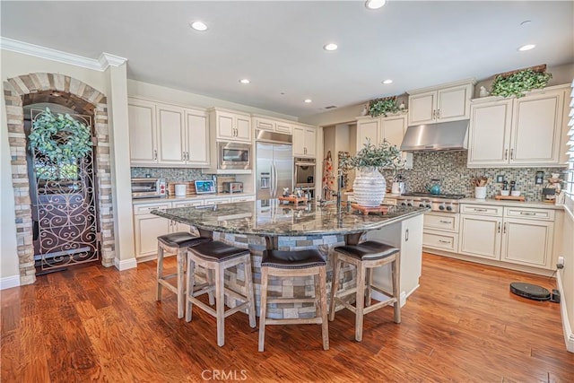 22348 Driftwood Ct, Saugus, CA 91350 - kitchen with built in appliances, under cabinet range hood, a kitchen breakfast bar, backsplash, and recessed lighting