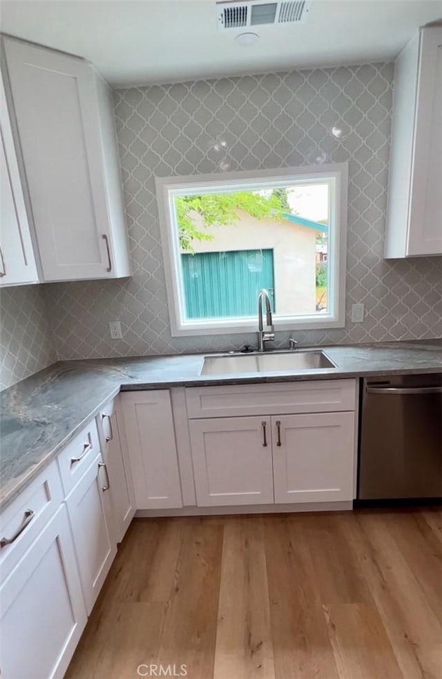 3520 Grand Ave, Huntington Park, CA 90255 - kitchen with stainless steel dishwasher, white cabinetry, healthy amount of natural light, and decorative backsplash
