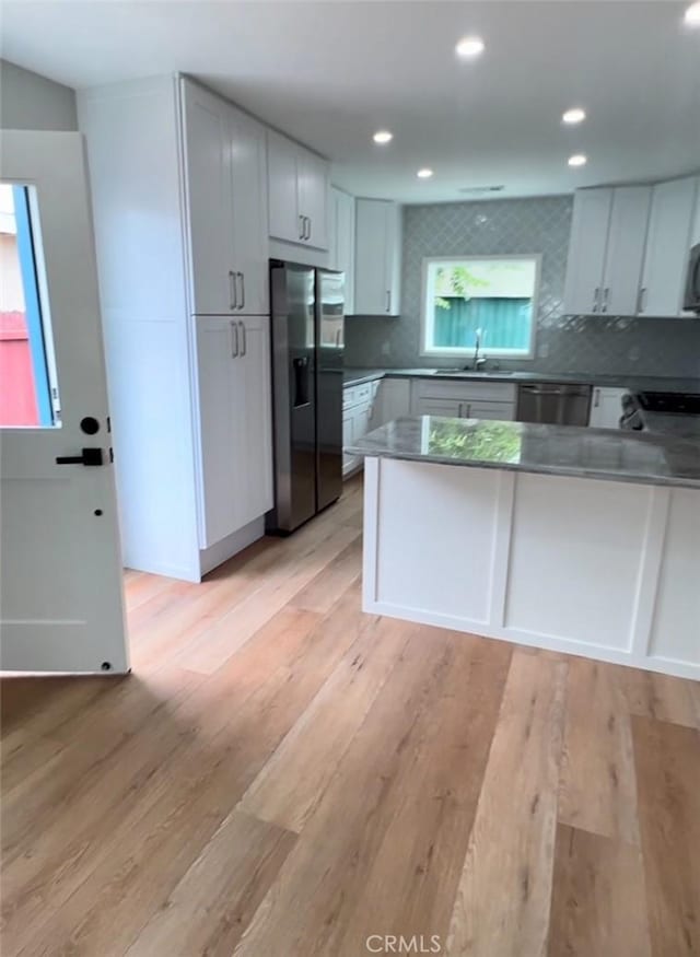 3520 Grand Ave, Huntington Park, CA 90255 - kitchen featuring appliances with stainless steel finishes, a peninsula, tasteful backsplash, light wood finished floors, and recessed lighting