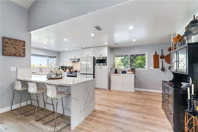 95 Buckskin Rd, Bell Canyon, CA 91307 - kitchen with stainless steel appliances, under cabinet range hood, a kitchen bar, white cabinetry, and a peninsula
