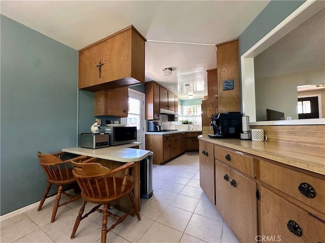 22709 Elm Ave, Torrance, CA 90505 - kitchen featuring under cabinet range hood, a peninsula, light countertops, and light tile patterned flooring