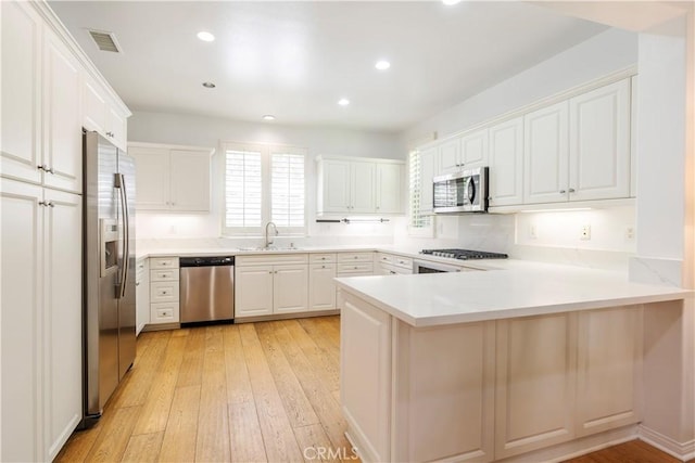 320 Bronze, Irvine, CA 92618 - kitchen featuring appliances with stainless steel finishes, a peninsula, light wood-style floors, white cabinets, and recessed lighting