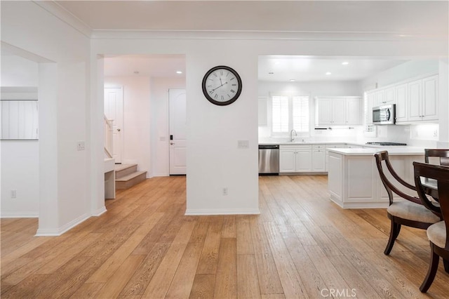 320 Bronze, Irvine, CA 92618 - kitchen featuring stainless steel appliances, light countertops, white cabinetry, light wood finished floors, and a kitchen bar