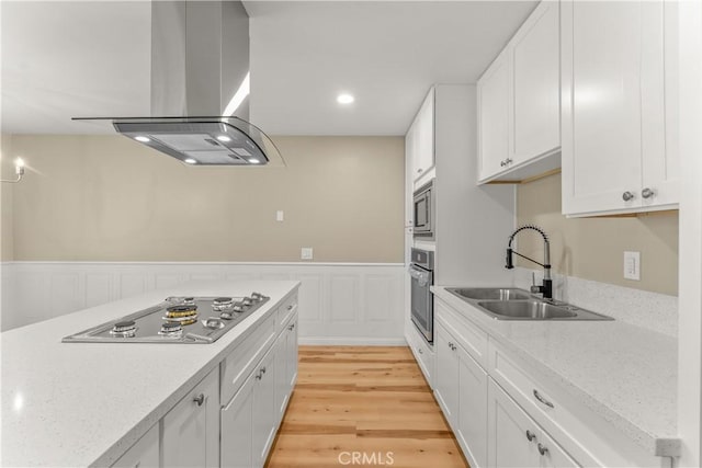 1446 Morgan Rd, San Bernardino, CA 92407 - kitchen featuring stainless steel appliances, island exhaust hood, wainscoting, white cabinets, and light wood-style floors
