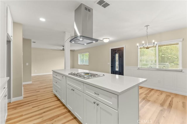 1446 Morgan Rd, San Bernardino, CA 92407 - kitchen with stainless steel gas stovetop, island exhaust hood, light wood finished floors, white cabinets, and a wainscoted wall
