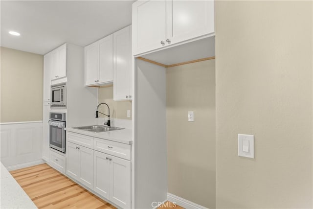 1446 Morgan Rd, San Bernardino, CA 92407 - kitchen featuring appliances with stainless steel finishes, white cabinets, light countertops, and a wainscoted wall