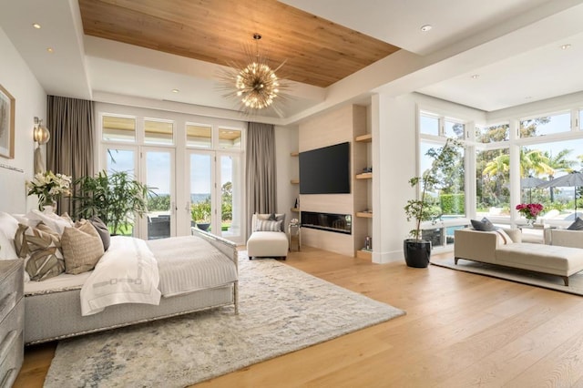 7888 Muirfield Way, Rancho Santa Fe, CA 92067 - bedroom with a tray ceiling, access to exterior, wood finished floors, a chandelier, and a glass covered fireplace
