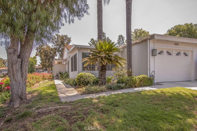 3179 Alta Vis Unit A, Laguna Woods, CA 92637 - view of home's exterior featuring an attached garage, stucco siding, a lawn, and concrete driveway