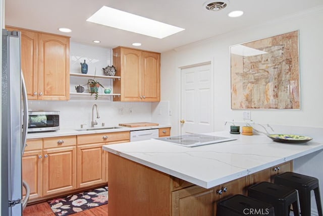 3179 Alta Vis Unit A, Laguna Woods, CA 92637 - kitchen featuring appliances with stainless steel finishes, a peninsula, a skylight, a kitchen bar, and wood finished floors