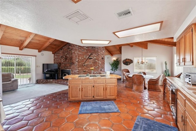 6020 Valley Sage Rd, Acton, CA 93510 - kitchen with tile counters, open floor plan, a wood stove, dishwashing machine, and a chandelier