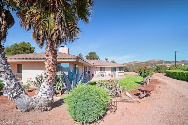 6020 Valley Sage Rd, Acton, CA 93510 - back of house featuring stucco siding, a chimney, a tile roof, and a mountain view