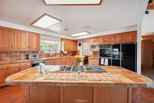 6020 Valley Sage Rd, Acton, CA 93510 - kitchen featuring black appliances, decorative backsplash, a center island, and tile counters