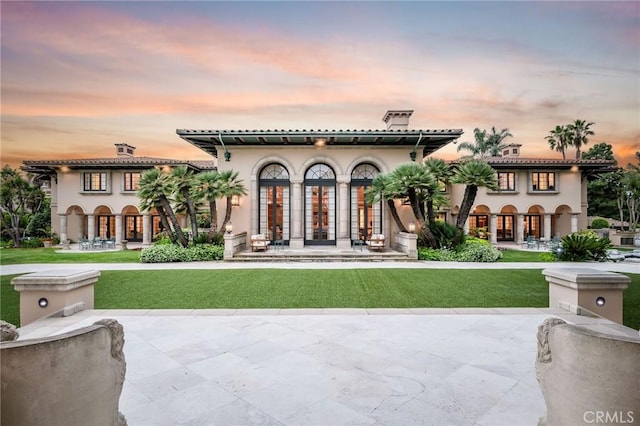 1129 Via Mirabel, Palos Verdes Estates, CA 90274 - back of house at dusk with french doors, a lawn, and stucco siding