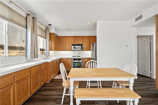 27545 Wellsley Way, Valencia, CA 91354 - kitchen with appliances with stainless steel finishes, dark wood-style flooring, decorative backsplash, recessed lighting, and brown cabinetry