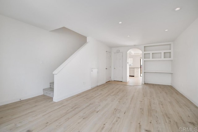 3414 Del Este Way, Oceanside, CA 92056 - unfurnished living room with arched walkways, wood finished floors, stairs, and recessed lighting