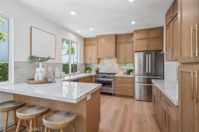 38 San Raphael, Dana Point, CA 92629 - kitchen with stainless steel appliances, light countertops, a peninsula, light wood-style floors, and decorative backsplash