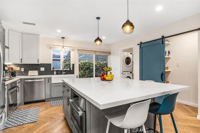 21225 Kent Ave, Torrance, CA 90503 - kitchen featuring stainless steel appliances, stacked washing machine and dryer, a barn door, light countertops, and recessed lighting