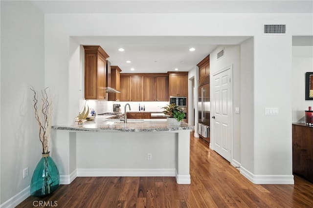 72 Shade Tree, Irvine, CA 92603 - kitchen with built in appliances, dark wood-style flooring, a peninsula, light stone counters, and brown cabinets