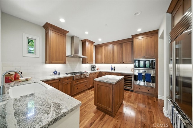 72 Shade Tree, Irvine, CA 92603 - kitchen with stainless steel appliances, wall chimney range hood, beverage cooler, light stone counters, and light wood-style flooring