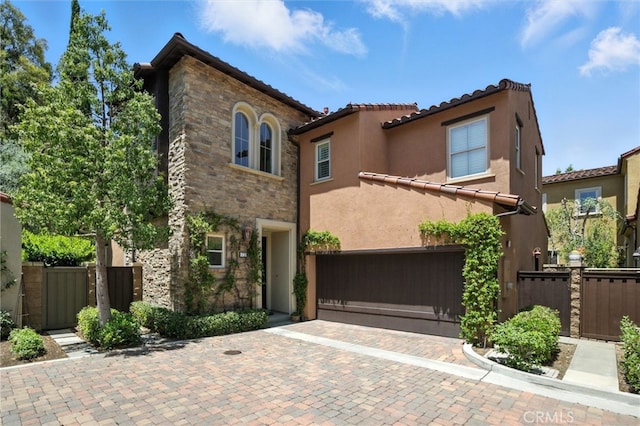72 Shade Tree, Irvine, CA 92603 - mediterranean / spanish-style house featuring a garage, stucco siding, decorative driveway, stone siding, and a gate