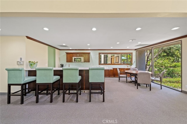 564 N Bellflower Blvd Unit 105, Long Beach, CA 90814 - kitchen featuring stainless steel microwave, carpet flooring, recessed lighting, light countertops, and a breakfast bar area
