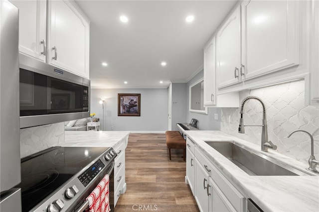 564 N Bellflower Blvd Unit 105, Long Beach, CA 90814 - kitchen featuring stainless steel appliances, backsplash, recessed lighting, white cabinets, and wood finished floors