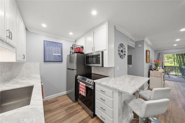 564 N Bellflower Blvd Unit 105, Long Beach, CA 90814 - kitchen featuring stainless steel appliances, ornamental molding, a breakfast bar, white cabinetry, and light wood finished floors