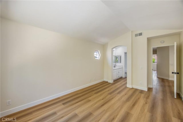 11142 Malone St, Rancho Cucamonga, CA 91701 - unfurnished bedroom with arched walkways, multiple windows, light wood-style flooring, vaulted ceiling, and ensuite bathroom