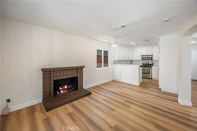 11142 Malone St, Rancho Cucamonga, CA 91701 - unfurnished living room with a brick fireplace, light wood-style floors, a ceiling fan, arched walkways, and recessed lighting