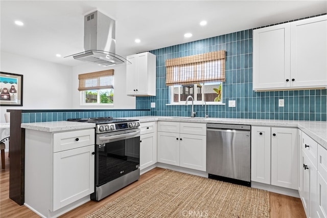 131 Gemini St, Lompoc, CA 93436 - kitchen with appliances with stainless steel finishes, island exhaust hood, a peninsula, light wood finished floors, and white cabinetry