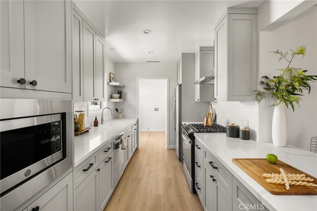 17216 Lorne St, Van Nuys, CA 91406 - kitchen with appliances with stainless steel finishes, open shelves, backsplash, light wood finished floors, and light stone counters