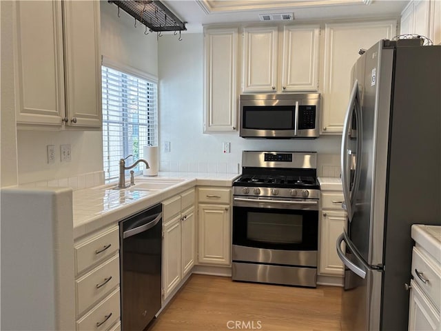 28741 La Triana, Laguna Niguel, CA 92677 - kitchen featuring stainless steel appliances, tile counters, light wood finished floors, and white cabinets