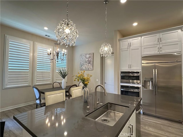 227 Carlow, Irvine, CA 92618 - kitchen with stainless steel appliances, a chandelier, light wood-style floors, white cabinetry, and recessed lighting
