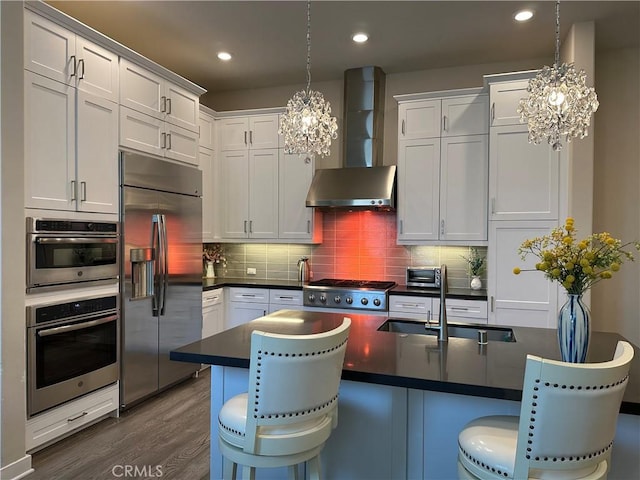 227 Carlow, Irvine, CA 92618 - kitchen with appliances with stainless steel finishes, wall chimney exhaust hood, a chandelier, dark countertops, and recessed lighting
