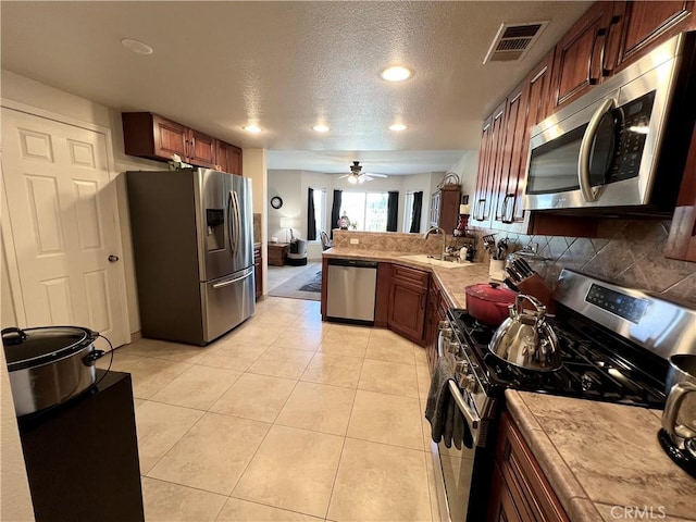 27347 Sahara Pl, Laguna Niguel, CA 92677 - kitchen featuring appliances with stainless steel finishes, a textured ceiling, light countertops, backsplash, and a peninsula
