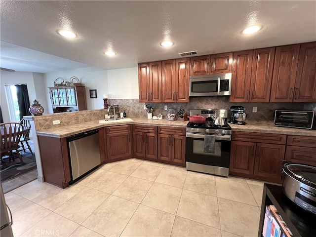 27347 Sahara Pl, Laguna Niguel, CA 92677 - kitchen featuring appliances with stainless steel finishes, a peninsula, backsplash, light tile patterned flooring, and recessed lighting