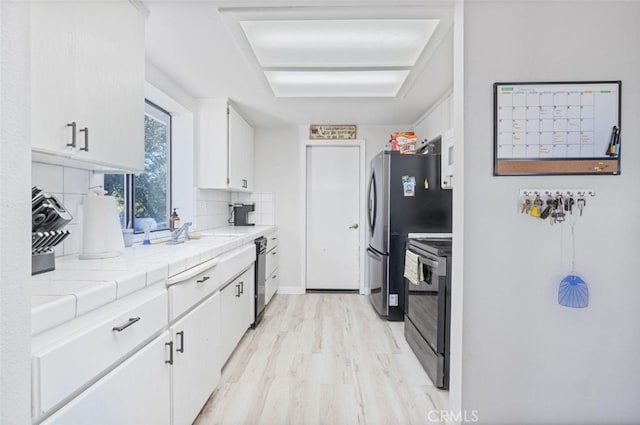33030 Rd 233, North Fork, CA 93643 - kitchen featuring stove, white cabinets, tile countertops, decorative backsplash, and light wood finished floors