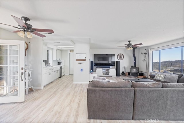 33030 Rd 233, North Fork, CA 93643 - living room with a ceiling fan, a wood stove, and light wood finished floors