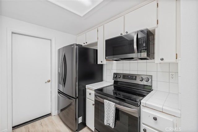 33030 Rd 233, North Fork, CA 93643 - kitchen featuring stainless steel appliances, tile countertops, light wood-type flooring, white cabinets, and decorative backsplash