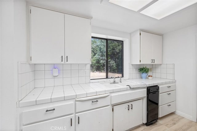33030 Rd 233, North Fork, CA 93643 - kitchen featuring white cabinetry, tasteful backsplash, tile countertops, and light wood-style floors