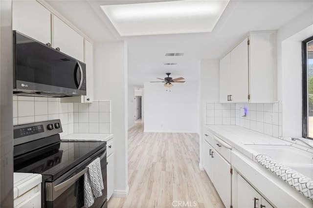 33030 Rd 233, North Fork, CA 93643 - kitchen featuring electric stove, black microwave, white cabinetry, light wood-style floors, and backsplash