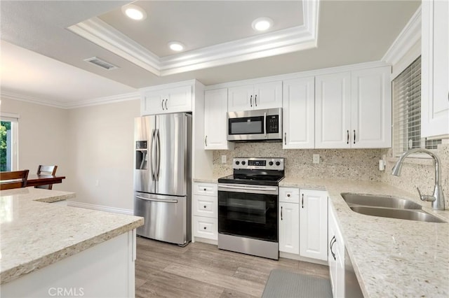 3034 Via Vis Unit A, Laguna Woods, CA 92637 - kitchen with appliances with stainless steel finishes, a raised ceiling, ornamental molding, white cabinetry, and backsplash