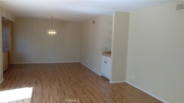 17305 Rosewood, Irvine, CA 92612 - unfurnished room with light wood-type flooring and a chandelier