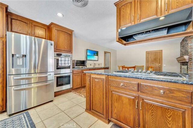 2528 Key Ct, Lancaster, CA 93536 - kitchen with stainless steel appliances, brown cabinets, light tile patterned flooring, under cabinet range hood, and recessed lighting