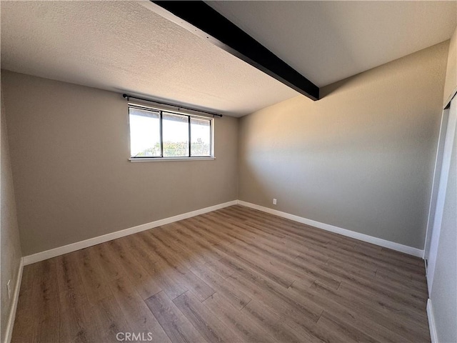 541 Frances Dr, Barstow, CA 92311 - empty room with wood finished floors, beam ceiling, and a textured ceiling