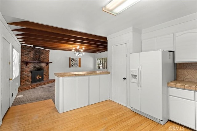 1869 Thrush Rd, Wrightwood, CA 92397 - kitchen with white refrigerator with ice dispenser, a peninsula, beam ceiling, white cabinets, and open floor plan