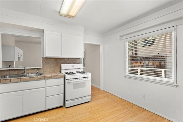 1869 Thrush Rd, Wrightwood, CA 92397 - kitchen featuring white range with gas stovetop, white cabinets, tile countertops, light wood finished floors, and decorative backsplash