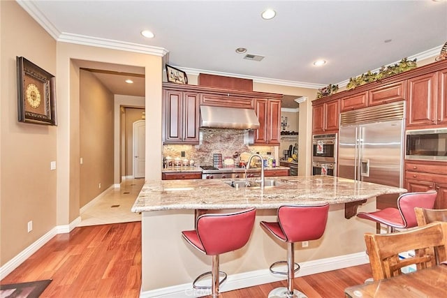 1482 Fergus, Claremont, CA 91711 - kitchen featuring built in appliances, under cabinet range hood, backsplash, a kitchen bar, and crown molding