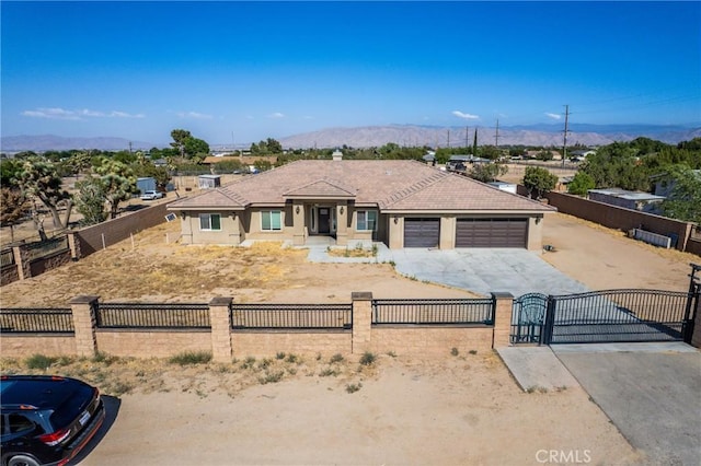 9121 6th Ave, Hesperia, CA 92345 - view of front facade with a gate, a fenced front yard, a mountain view, concrete driveway, and a garage