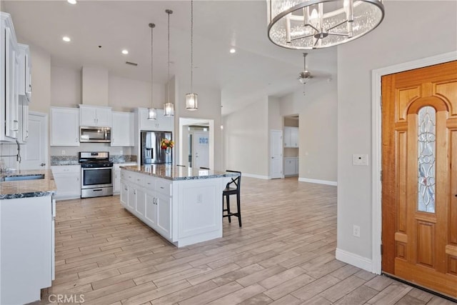9121 6th Ave, Hesperia, CA 92345 - kitchen with stainless steel appliances, a towering ceiling, a kitchen island, light wood-style floors, and a breakfast bar